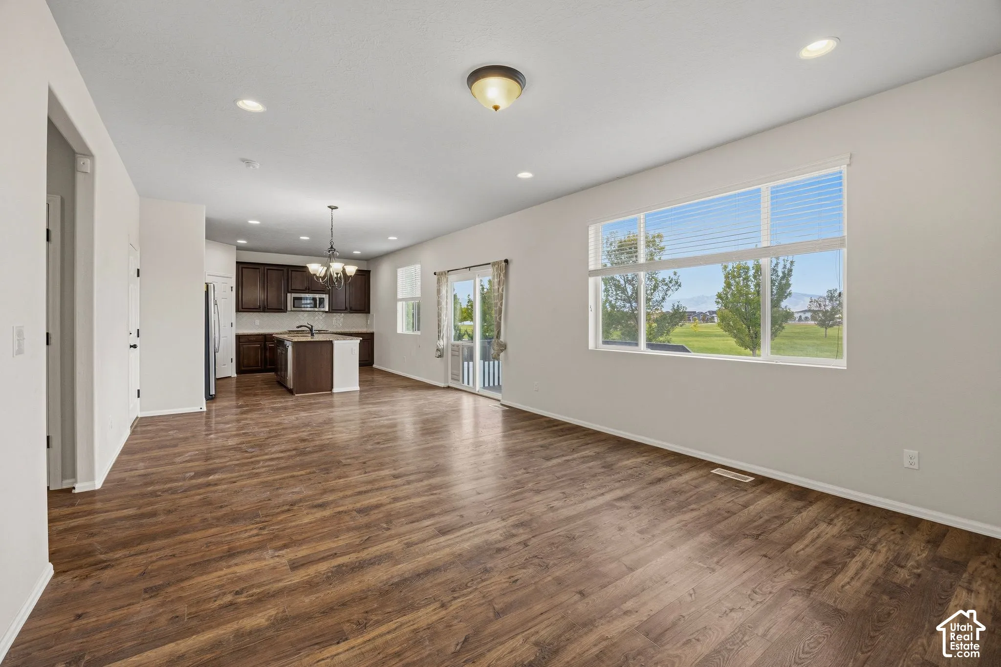 Open-concept layout featuring wood-finish flooring, recessed lighting, and a kitchen with dark wood cabinetry and a central island