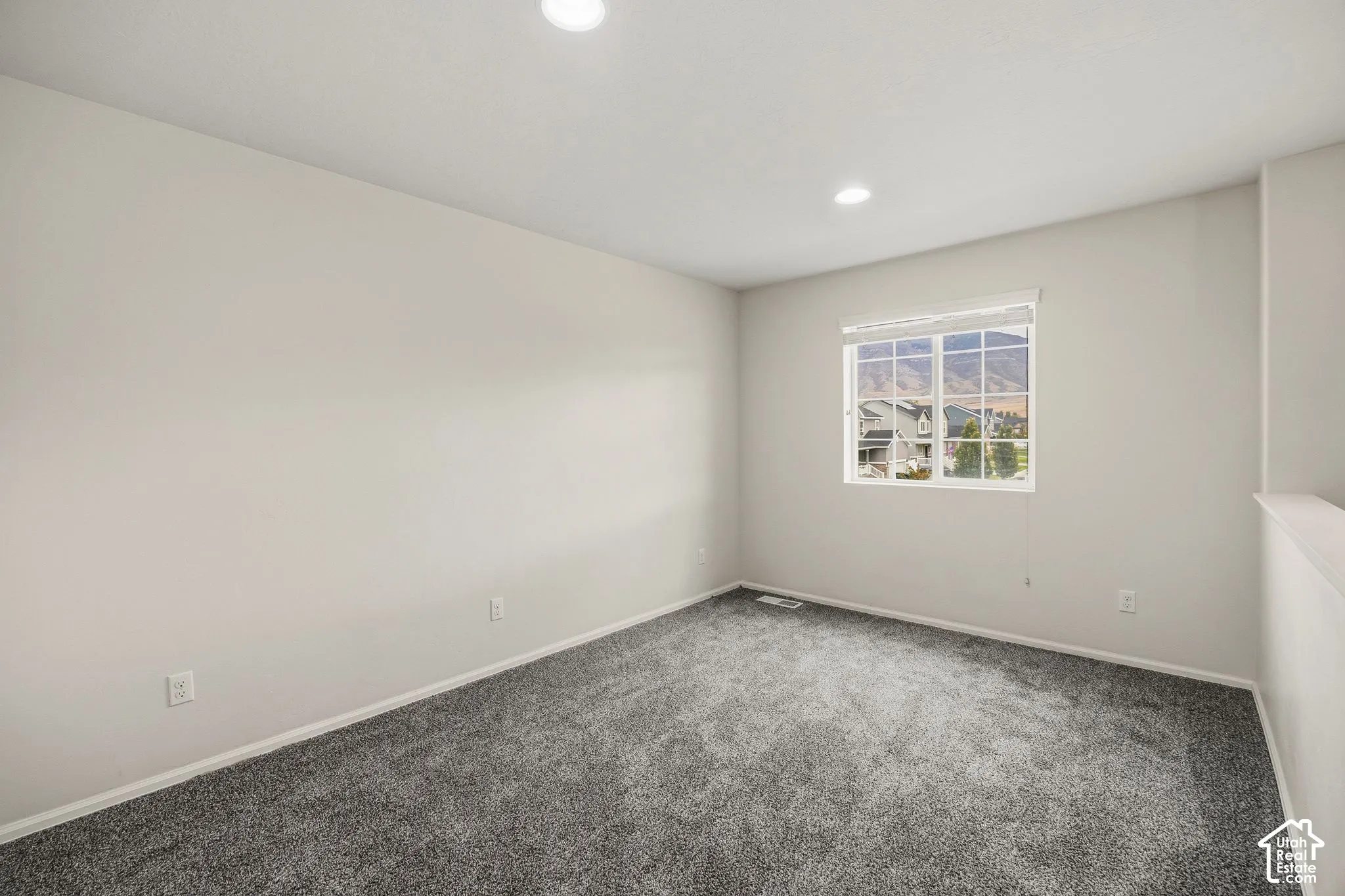 Loft with recessed lighting illuminating a spacious room with carpet flooring
