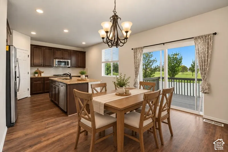 AI Staged Kitchen/Dining featuring dark wood cabinetry, a central island with stone-finish countertops, stainless steel appliances, wood-finish flooring, and sliding glass doors opening to an exterior deck