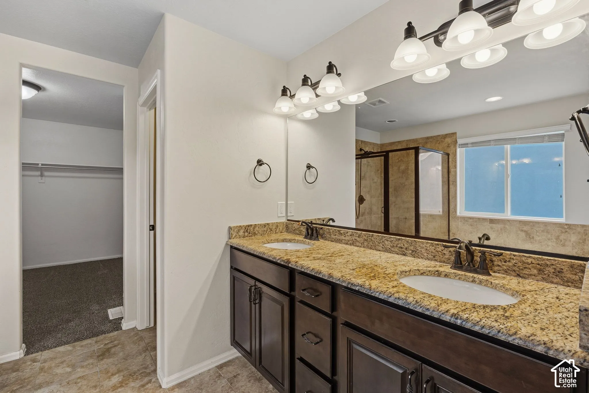 Primary bath with dual vanity with stone-finish countertop, undermount sinks, and dark wood-finish cabinetry