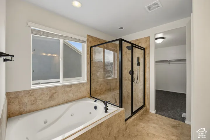 Primary suite w/jetted soaking tub, separate tiled shower with glass enclosure, tiled flooring, and recessed lighting