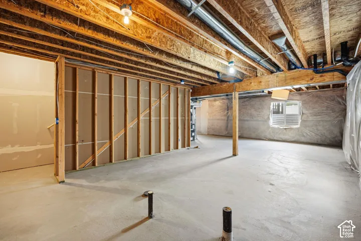 Unfinished lower level featuring exposed wood joists, concrete flooring, and partial wall framing
