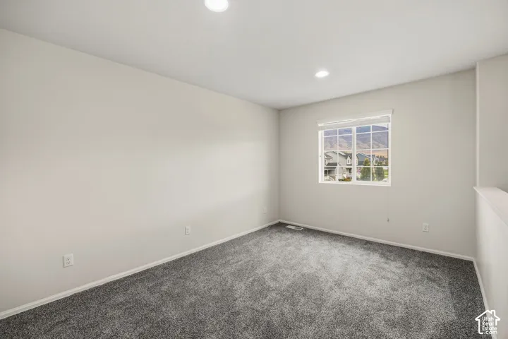 Loft with recessed lighting illuminating a spacious room with carpet flooring
