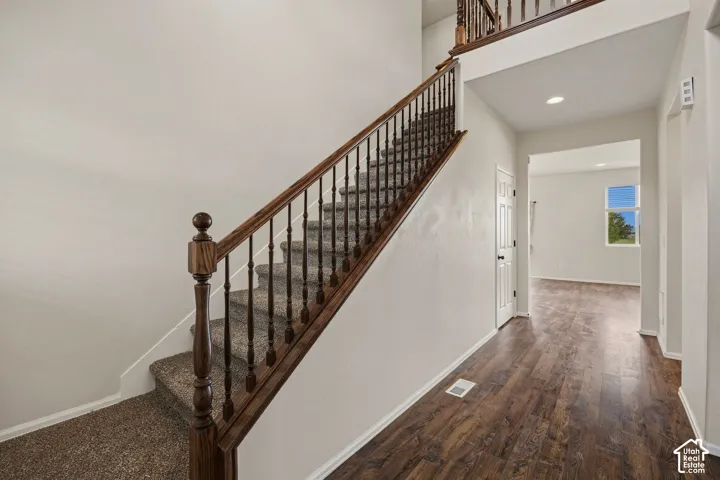 Foyer with wood-finish flooring, recessed lighting, carpeted staircase, and wood handrail with balusters