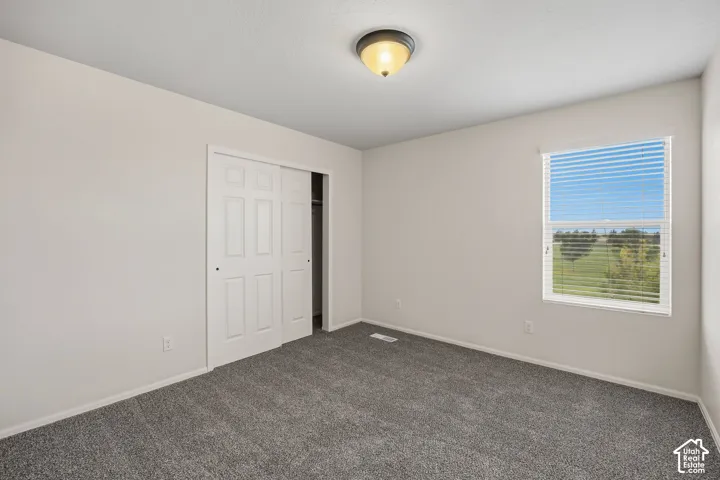Neutral-toned walls, gray carpet, sliding closet doors, and a window with horizontal blinds