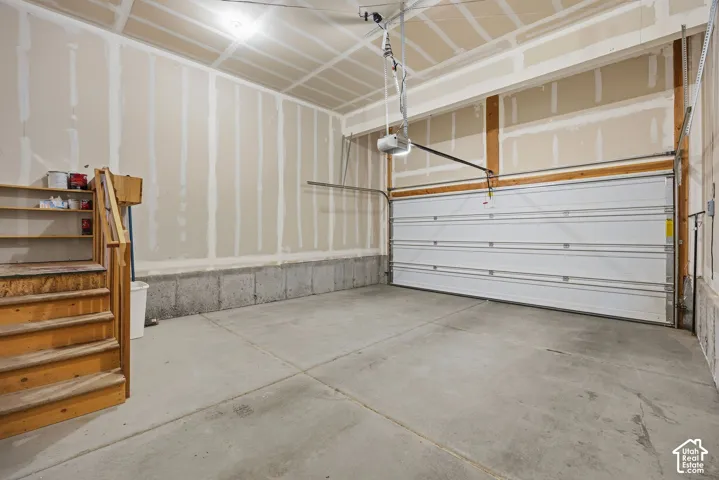 Concrete flooring with a white sectional garage door and built-in wooden staircase