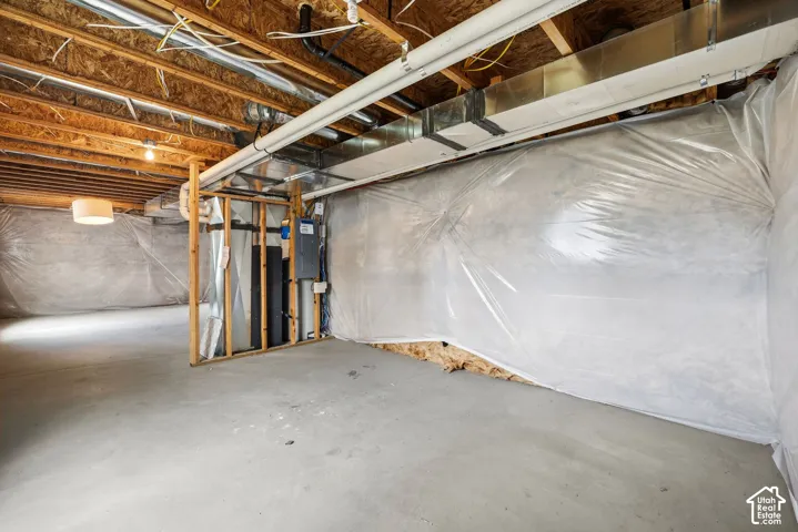 Unfinished basement with exposed wood joists, concrete flooring, and visible utility infrastructure