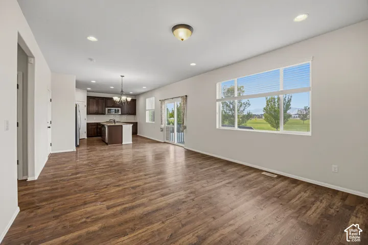 Open-concept layout featuring wood-finish flooring, recessed lighting, and a kitchen with dark wood cabinetry and a central island