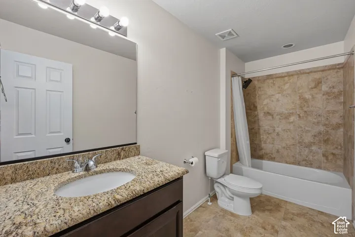 Bathroom featuring a vanity with an oval sink and granite countertop, a full bathtub with a tiled shower surround, and tile flooring