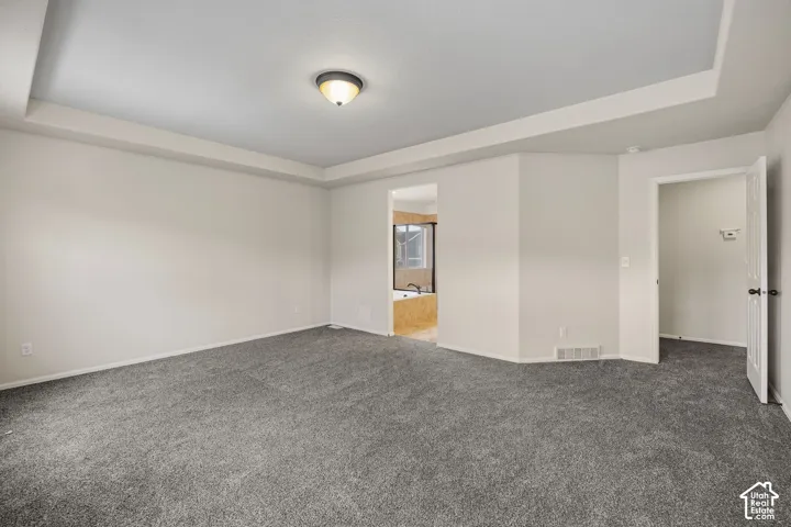 Primary bedroom with ray ceiling, recessed lighting, neutral wall tones, carpeting and ensuite