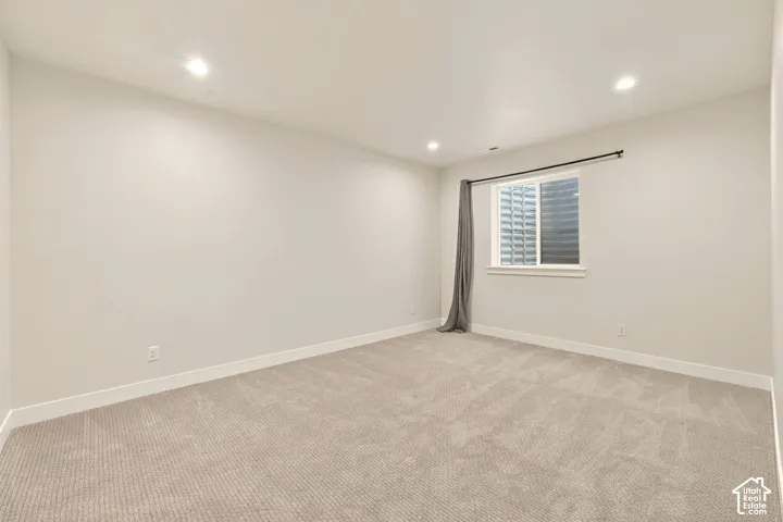 Recessed lighting, light-toned walls, and neutral carpet flooring