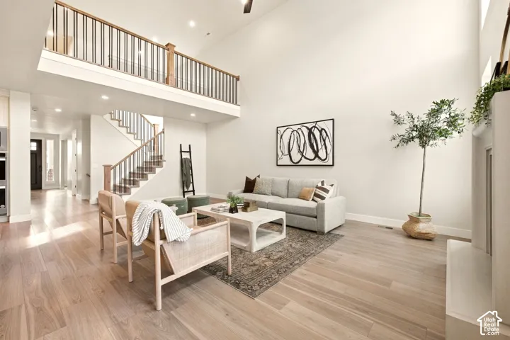Soaring ceilings with recessed lighting, wood-finish flooring, a contemporary fireplace, and a lofted area with a wood and metal railing