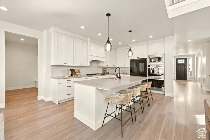 Gourmet kitchen with white cabinetry, a large center island, and stainless steel appliances