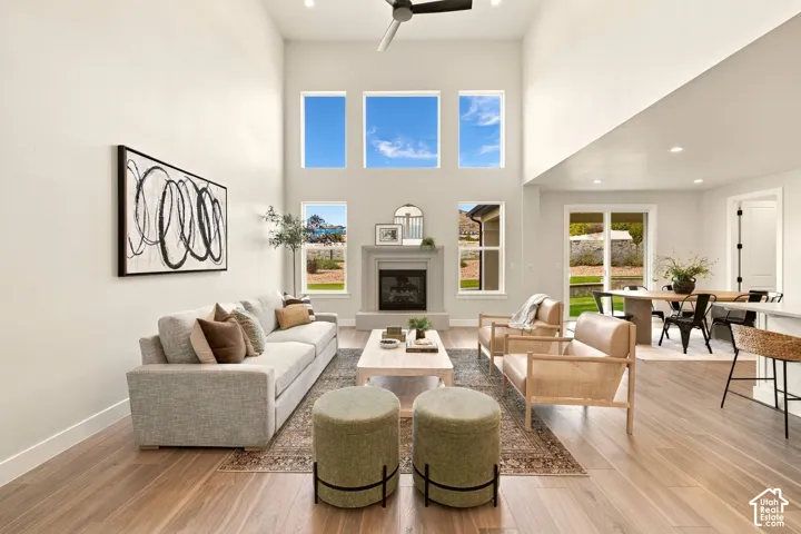 Vaulted ceiling with a ceiling fan, light wood-finish flooring, and a fireplace with a stone-finish mantel