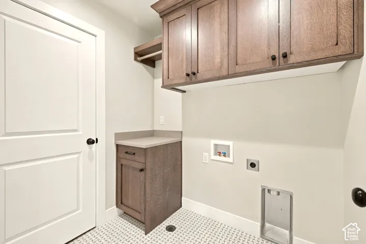 Laundry area with patterned floor tile, wood-finish cabinetry, built-in shelving, and a solid surface countertop