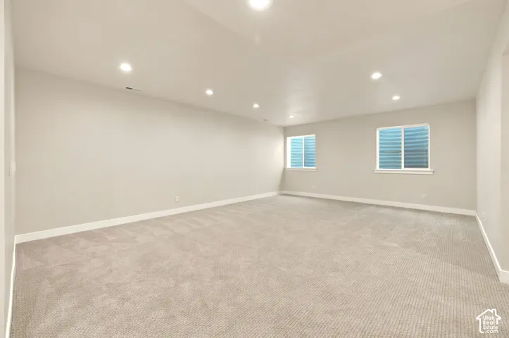 Spacious room featuring neutral carpeting, recessed ceiling lighting, and two windows