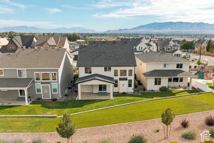 Expansive backyard featuring a manicured lawn, established landscaping, and a covered patio