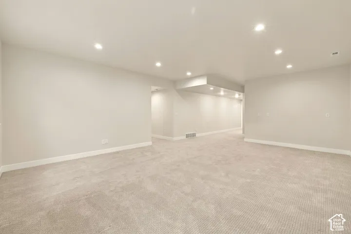 Spacious room with recessed lighting, light-toned carpeting, and neutral wall tones