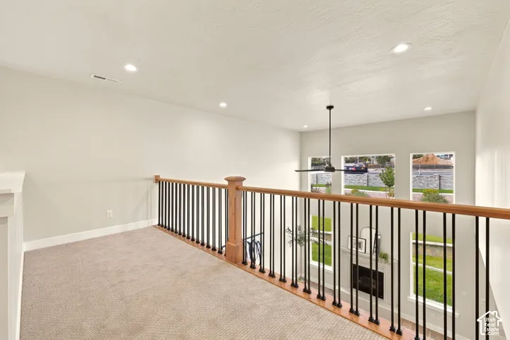 Carpeted loft space with wood-finish and wrought iron railing, recessed lighting, and a modern ceiling fan