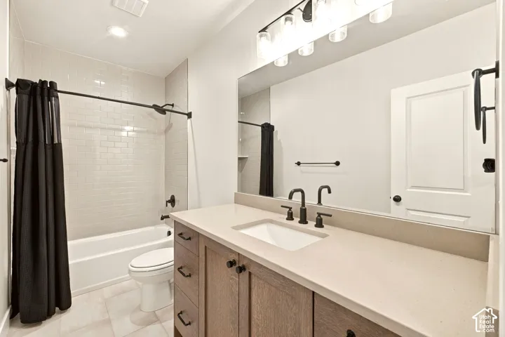 Spacious bathroom featuring a single vanity with wood-finish cabinetry, a large vanity mirror, a bathtub with a white subway tile surround, and a toilet