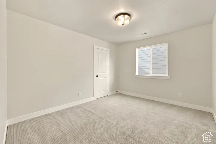 Neutral tone wall paint, light gray carpeting, white trim, recessed lighting, and a white framed window