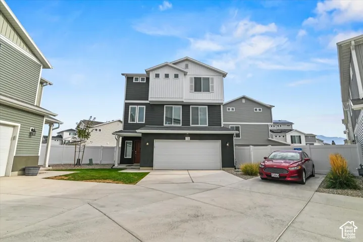Contemporary exterior with dark and light siding, white trim accents, attached garage, and concrete driveway