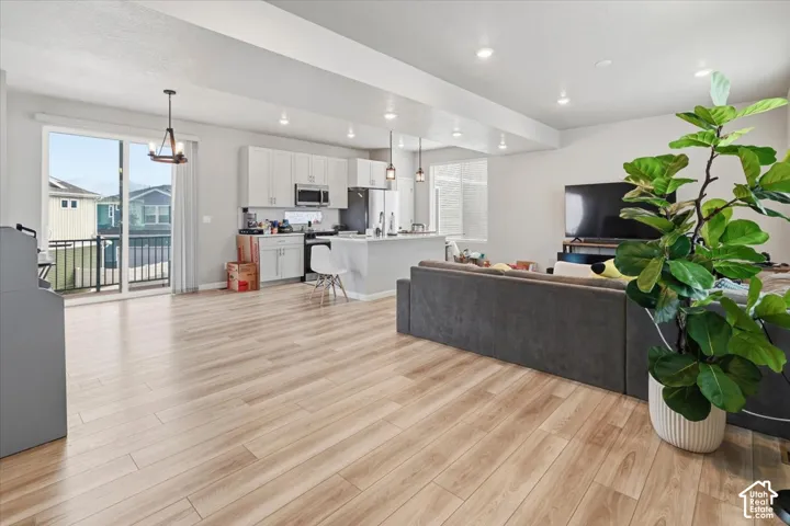 Open-concept living space with wood-finish flooring, recessed lighting, and a sliding glass door to an outdoor balcony