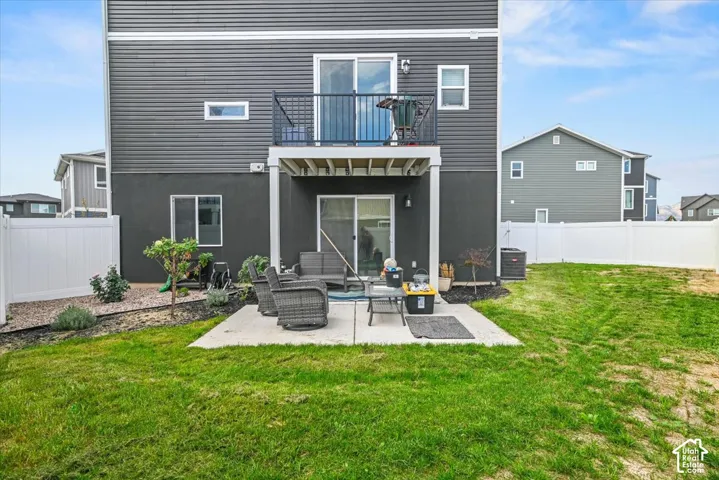 Concrete patio with direct outdoor access via sliding glass door, a privacy fence, and a second-story balcony with metal railing