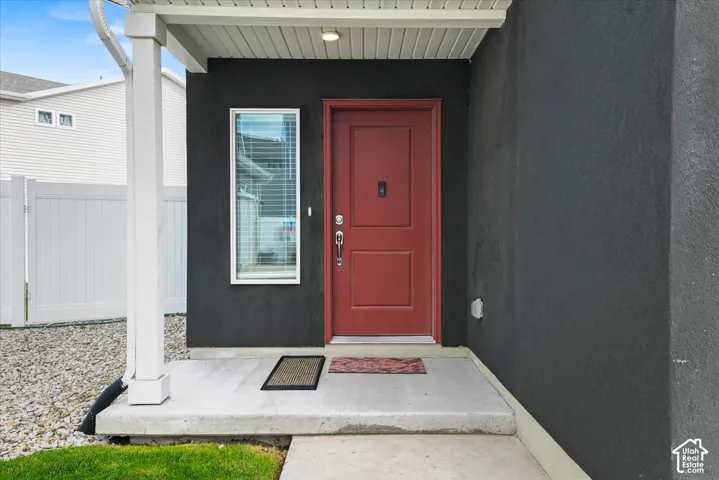 Covered entry with a red panel door and sidelight window