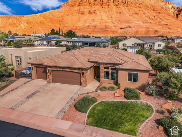 Stucco exterior with stone accents, tile roof, multi-car garage, and desert landscaping