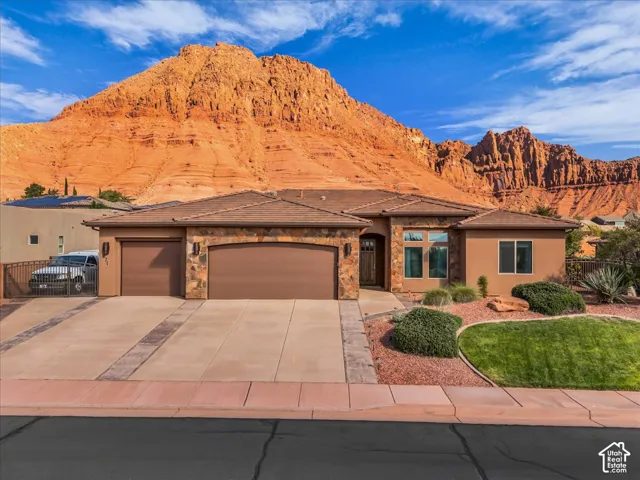 Stucco exterior with stone accents, an attached two-car garage, and a concrete driveway with decorative banding