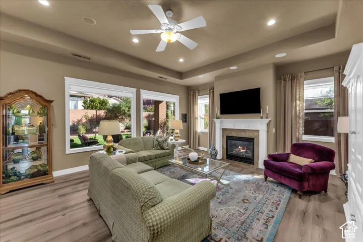 Spacious living area featuring wood-finish flooring, a ceiling fan, a gas fireplace with a white mantel, and recessed lighting