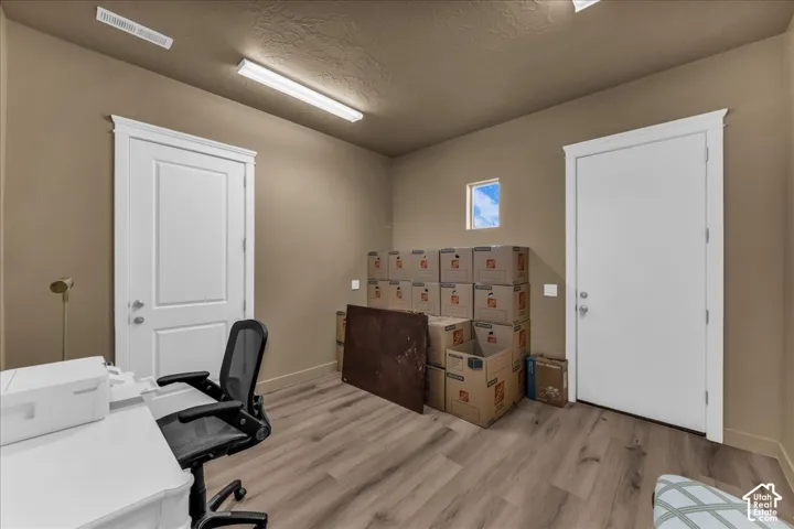 Wood-finish flooring, two panel doors with white trim, a small window, and overhead lighting