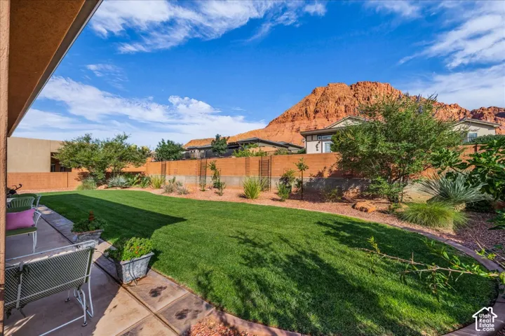 Expansive backyard featuring a manicured lawn, established landscaping, and a paver patio