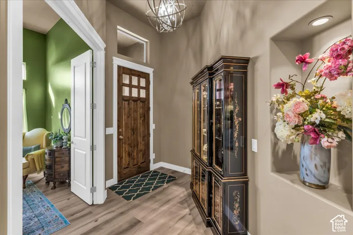 Wood-finish flooring, recessed wall niche, and a rich wood front door with glass panels