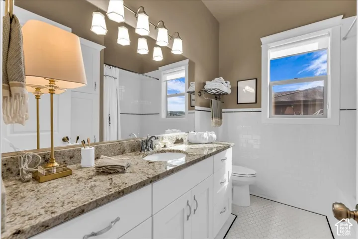 Double vanity with granite countertop, white cabinetry, and undermount sinks