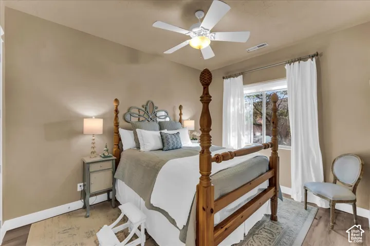 Window with natural light, wood-finish flooring, ceiling fan with integrated lighting, neutral wall tones, and white trim
