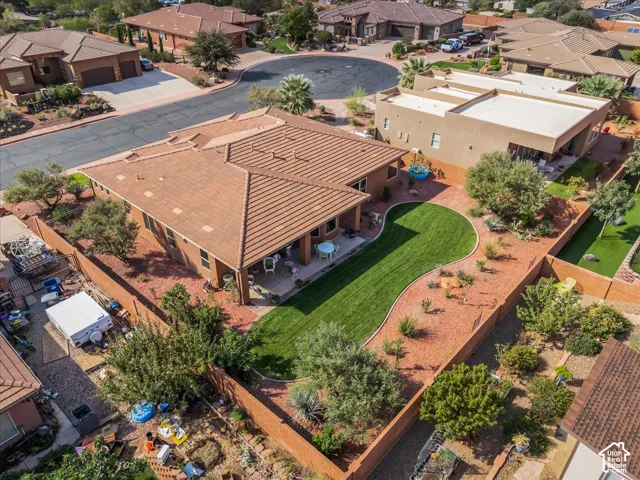 Spacious backyard with a curved manicured lawn, red rock landscaping, and a covered patio