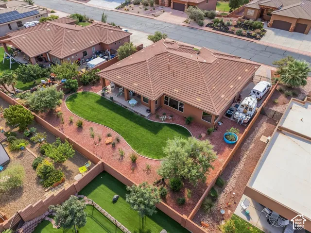 Expansive backyard featuring a manicured lawn, established landscaping, and a covered patio