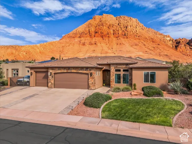 Stucco and stone exterior with a tile roof, two garage doors, and a decorative concrete driveway