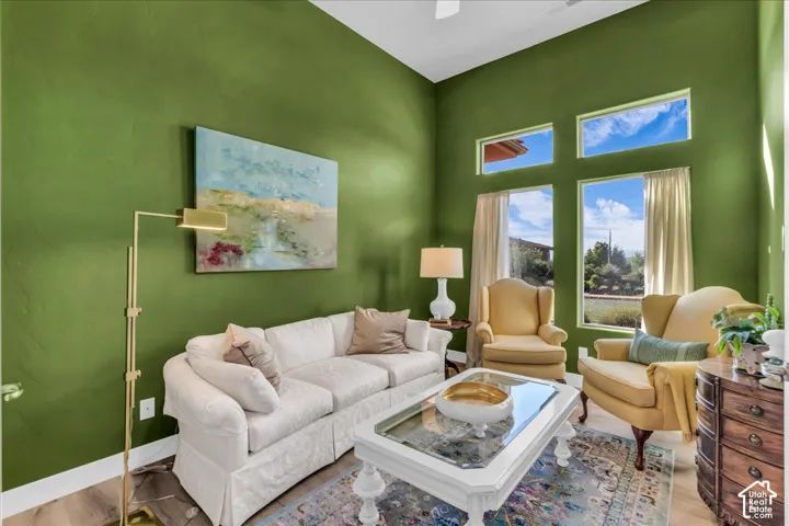 Vaulted ceiling, wood-finish flooring, multiple windows, built-in ceiling fan, and decorative wall paneling