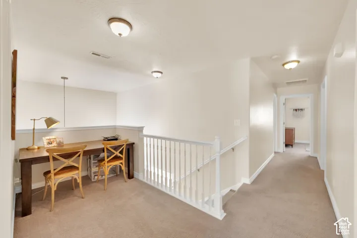 Carpeted hallway with white railing and neutral wall tones