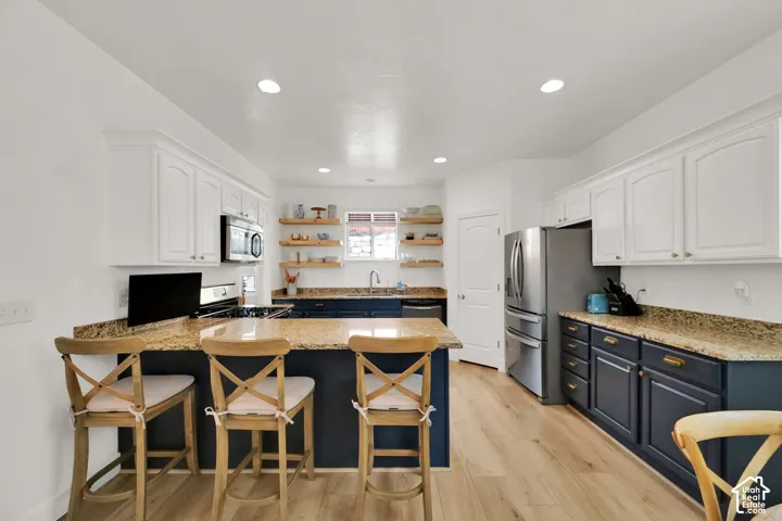 Kitchen featuring light wood-finish flooring, white upper cabinetry, dark lower cabinetry, and recessed lighting