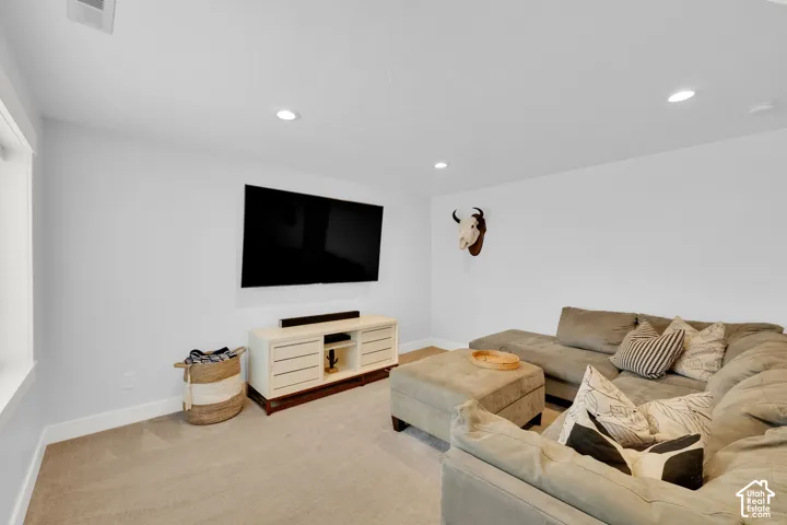 Recessed lighting illuminates the room, featuring a wall-mounted television and a media console