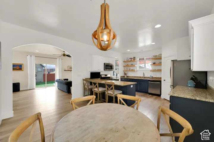 Kitchen featuring wood-finish flooring, two-tone cabinetry, stainless steel appliances, granite countertops, and open shelving