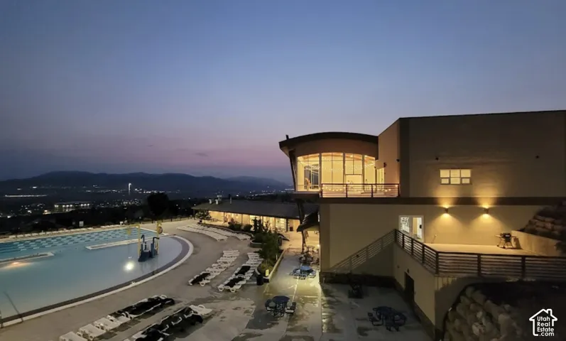 Multi-level exterior structure featuring large-scale windows, expansive terrace space with metal railings, and an oversized outdoor swimming pool with integrated hardscaping