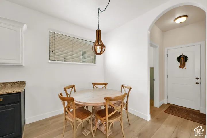 Wood-finish flooring with white baseboards, a wood pendant light fixture, and an arched doorway