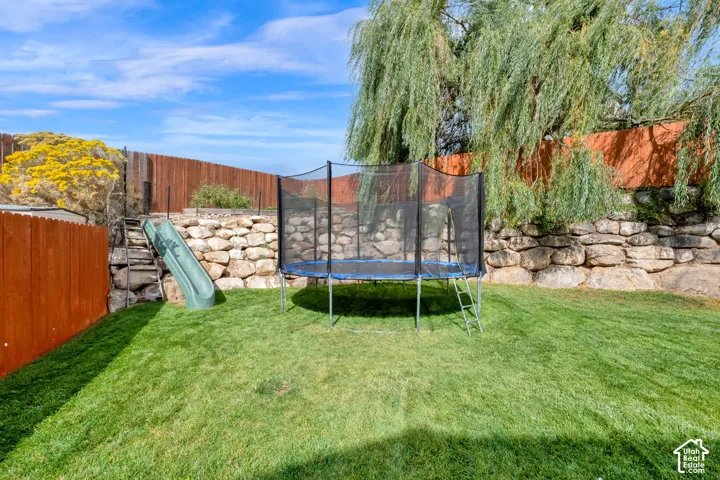 Expansive green lawn surrounded by wood fencing and a stacked stone retaining wall