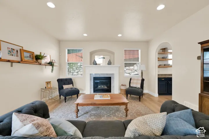 Living area featuring recessed lighting, a fireplace with a white mantel, and wood-finish flooring
