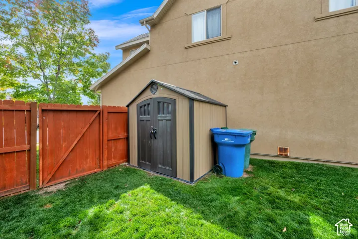Backyard space featuring a storage shed with double doors, wood privacy fencing, and a stucco exterior